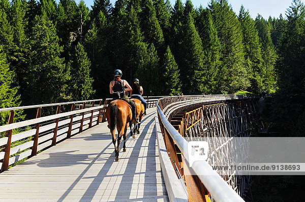 Two women on horses ride over the newly renovated Kinsol Trestle in Shawnigan Lake  BC.