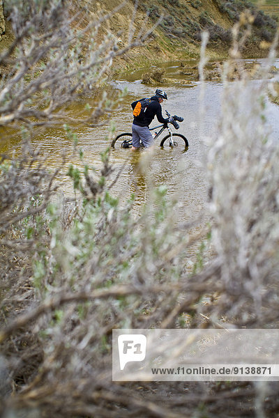 A man pushes his mountain bike through spring run off conditions on the Maah Daah Hey Trail North Dakota