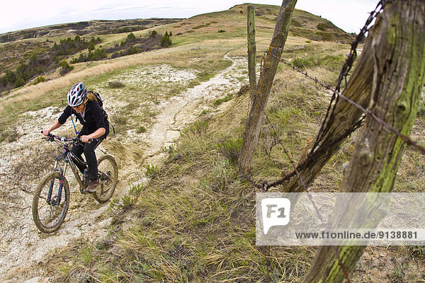 A female mountain biker follows a perfect ribbon of singletrack. Maah Daah Hey Trail  North Dakota