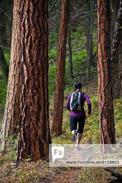 A young asian woman trail running in the 3 Blind Mice trail system. Penticton  BC
