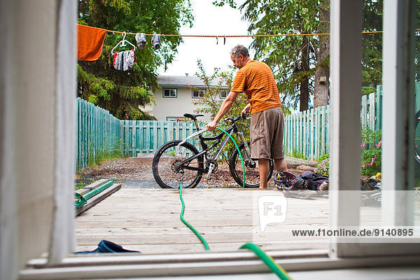 A middle aged man washing down his mountain bike after a muddy ride in Golden  BC