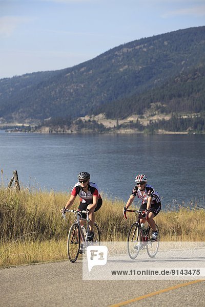 Teenage female Road cyclists over looking Kalamalka Lake  near Vernon  Okanagan  British Columbia  Canada