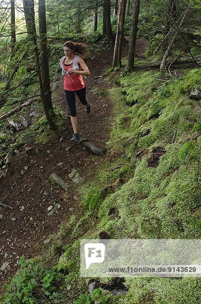 Woman trail running the Jug Island Trail. Belcarra Regional Park  Port Moody  British Columbia  Canada