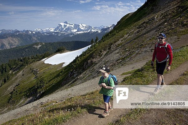 Young Boy and Father Hiking on Skyline Divide Trail  Mt Shuksan in Distance  Mount Baker Wilderness Area  Washington State  United States of America