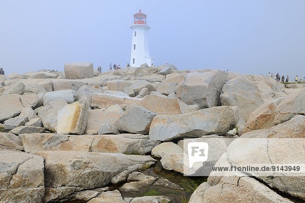 Lighthouse and rocky shoreline in fog  Peggy's Cove  Nova Scotia  Canada