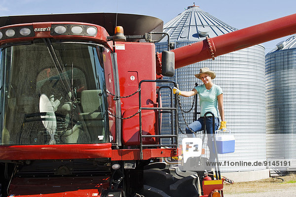 a farm girl on the deck of a combine in a farmyard prepares for a day of harvesting  near Dugald  Manitoba  Canada