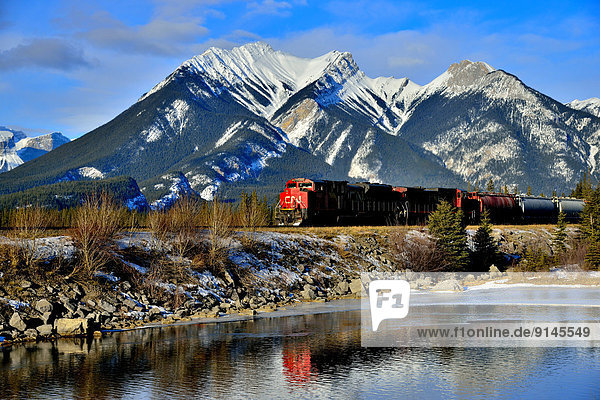 A Canadian National freight train passing a snow-capped rocky mountain on the main rail line through Jasper National Park in Alberta  Canada.