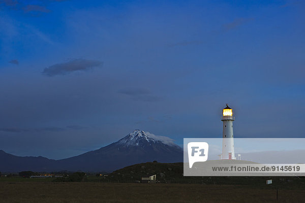 Cape Egmont Lighthouse with Mt Egmont behind seen from Cape Egmont  Taranaki  North Island  New Zealand.