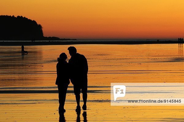 A young couple at sunset about to kiss while on Chesterman Beach near Tofino  BC.