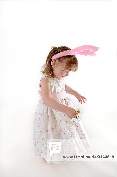 Little girl in bunny ears holding a flower