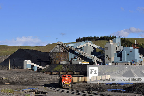 A wide angle image of a coal processing plant with piles of coal and a Canadian National freight train being loaded near Hinton Alberta  Canada.
