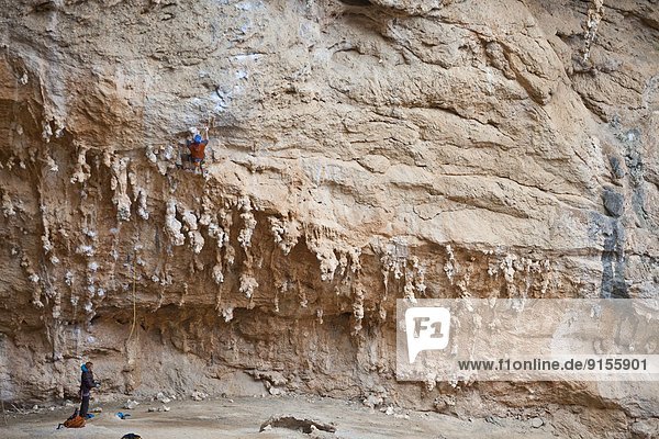 A male climber ascends through the wild limestone rock formations of Lolita 7a  Sikati Cave  Kalymnos  Greece