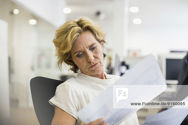 Relaxed businesswoman reading documents in office