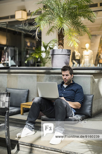 Mittlerer Erwachsener Geschäftsmann mit Laptop im Cafe