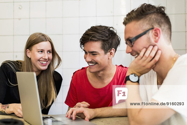 Glückliche junge Geschäftsleute mit Laptop im Kreativbüro