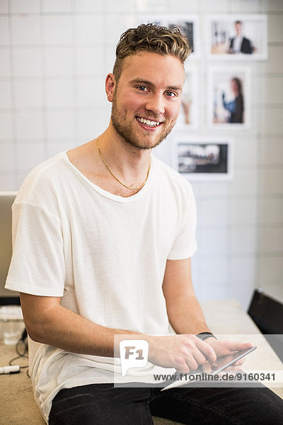 Porträt eines glücklichen jungen Geschäftsmannes mit digitalem Tablett im neuen Büro
