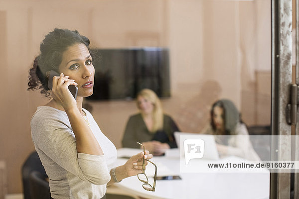 Businesswoman using mobile phone while looking away in creative office