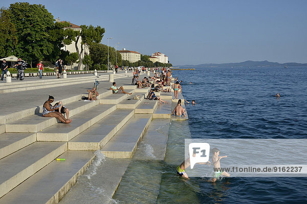 Visitors basking in the evening sun at the Sea Organ by architect Nikola Ba?i?  Zadar  Dalmatia  Croatia