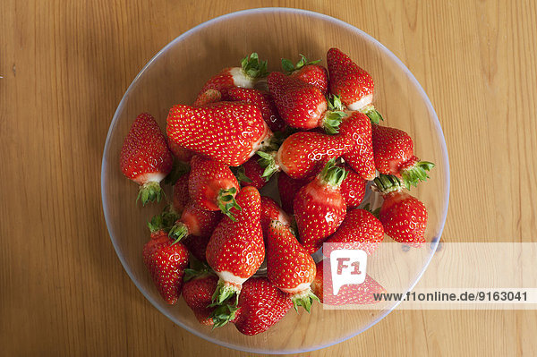 Frische Erdbeeren auf einem Glasteller auf Holzuntergrund