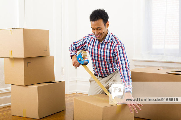 Mixed race man packing cardboard boxes