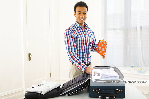 Mixed race businessman packing suitcase
