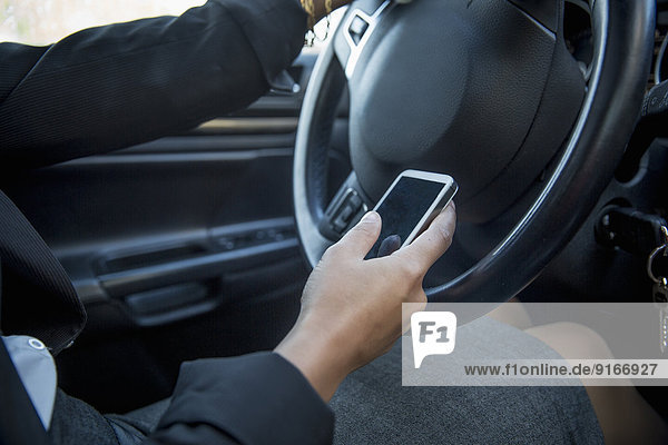Mixed race businesswoman using cell phone while driving