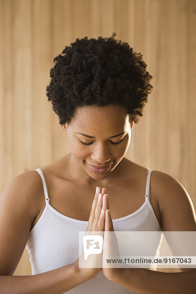 Close up of serene Black woman with hands in prayer position