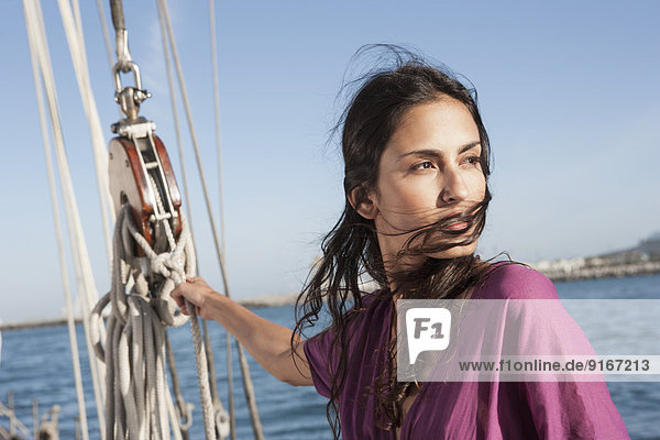 Caucasian woman hoisting sail on sailboat