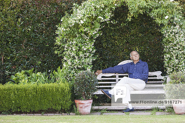 Senior Caucasian man sitting on garden bench