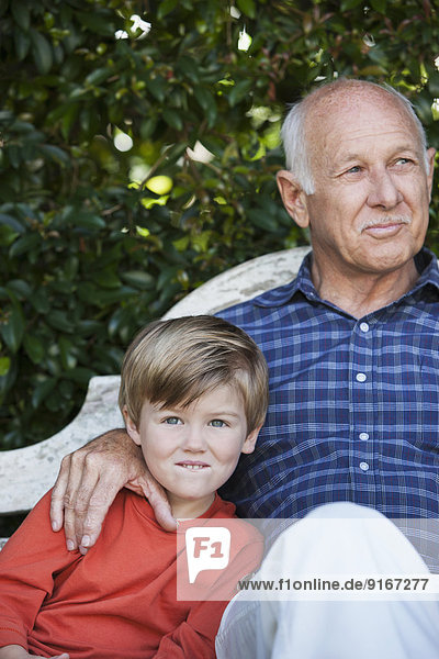 Caucasian boy sitting with grandfather on bench