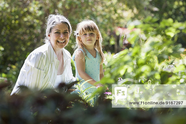 Grandmother and granddaughter smiling in garden