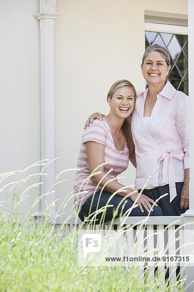 Caucasian mother and daughter smiling on porch