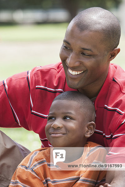 African American father and son sitting in park
