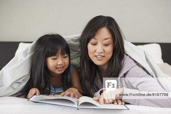 Mother and daughter reading in bed