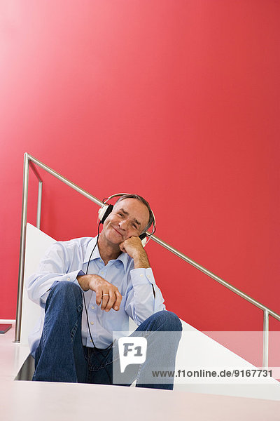 Man listening to headphones on stairs