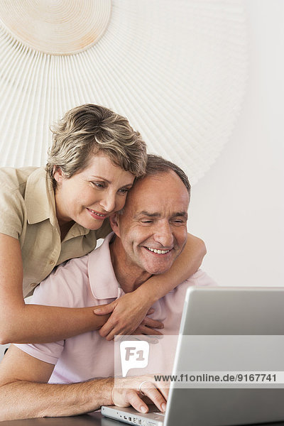 Woman hugging husband at laptop