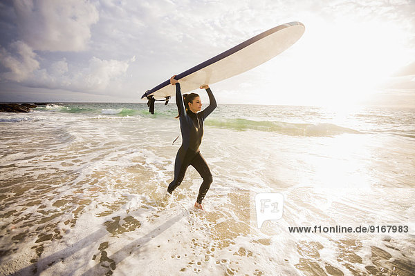 Caucasian surfer carrying board in waves
