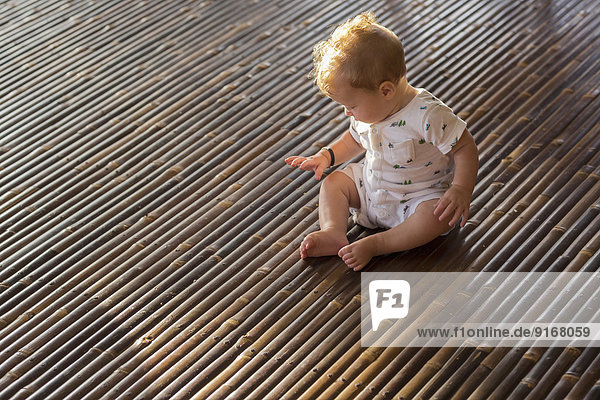 Caucasian baby playing on bamboo floor