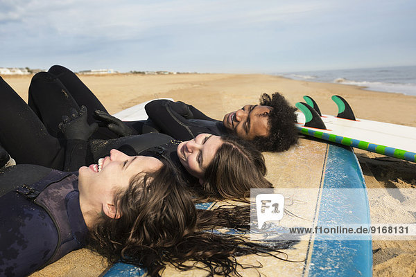 Surfers laying on boards on beach