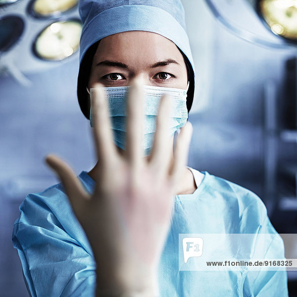 Caucasian surgeon pulling on glove in operating room