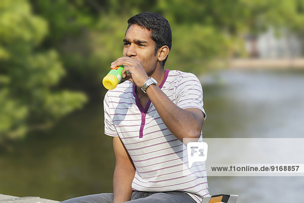 Sri Lankan man drinking juice on balcony