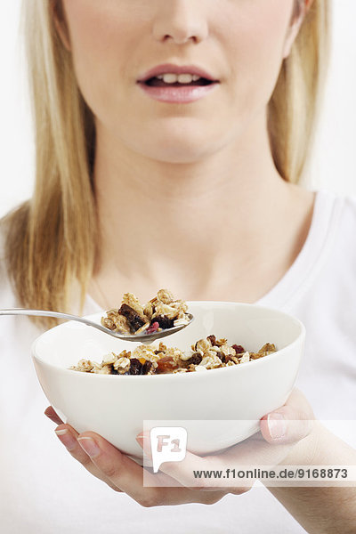 Caucasian woman eating bowl of muesli cereal