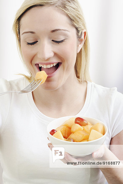 Caucasian woman eating bowl of fruit salad