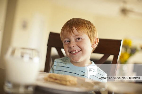 Caucasian boy giggling at dinner table