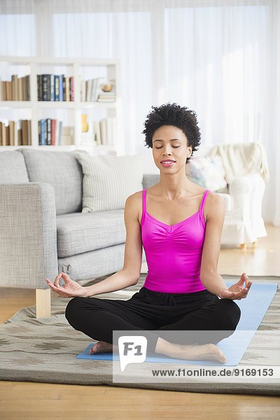 Black woman meditating on yoga mat