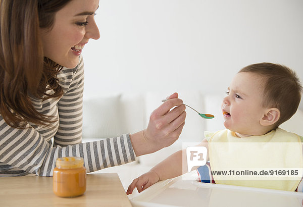 Mother feeding baby in high chair