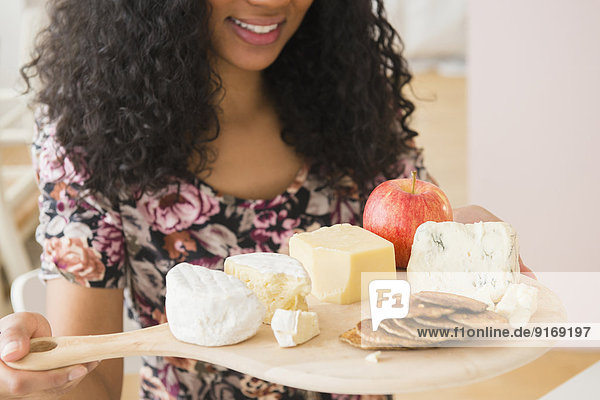 Mixed race woman carrying fruit and cheese board