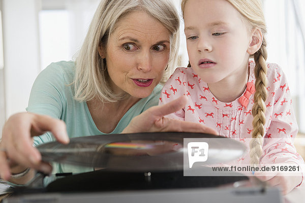 Senior Caucasian woman and granddaughter listening to records