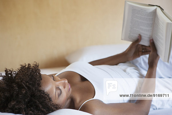 African American woman reading on bed