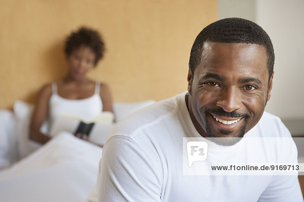 African American man sitting on bed